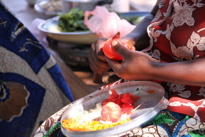 A woman peels a tomato to add to a dish of tomato, pumpkin and vegetables, Barotse floodplain, Zambia. (Credit: Bioversity International/E.Hermanowicz)